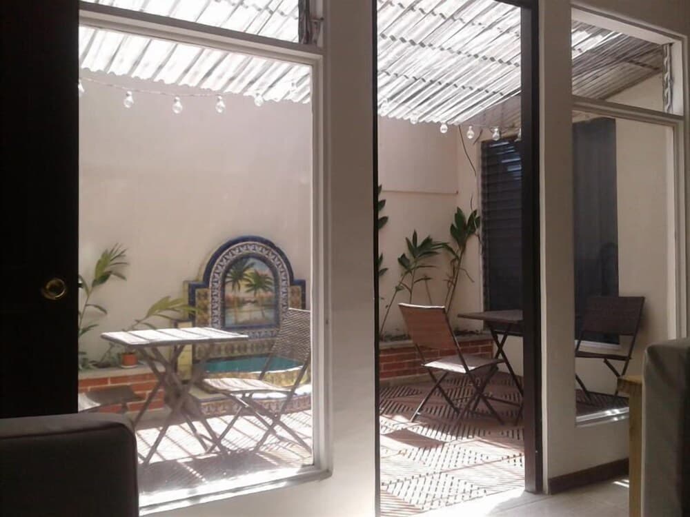 A cozy indoor-outdoor patio space features string lights, tropical-themed decor, and comfortable seating, ideal for travelers seeking a relaxing retreat in a charming urban setting.