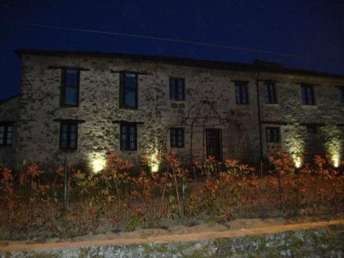 A rustic stone building illuminated at night with warm lights creates a cozy atmosphere, ideal for travelers seeking a serene countryside retreat with charming architectural details and garden accents.