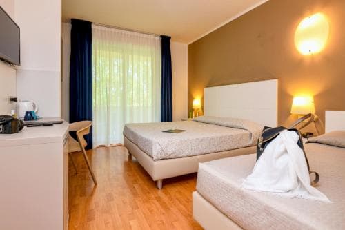 A cozy hotel room with warm lighting, wooden floors, a neatly made bed, and a desk area creates an inviting atmosphere ideal for travelers seeking comfort and relaxation.