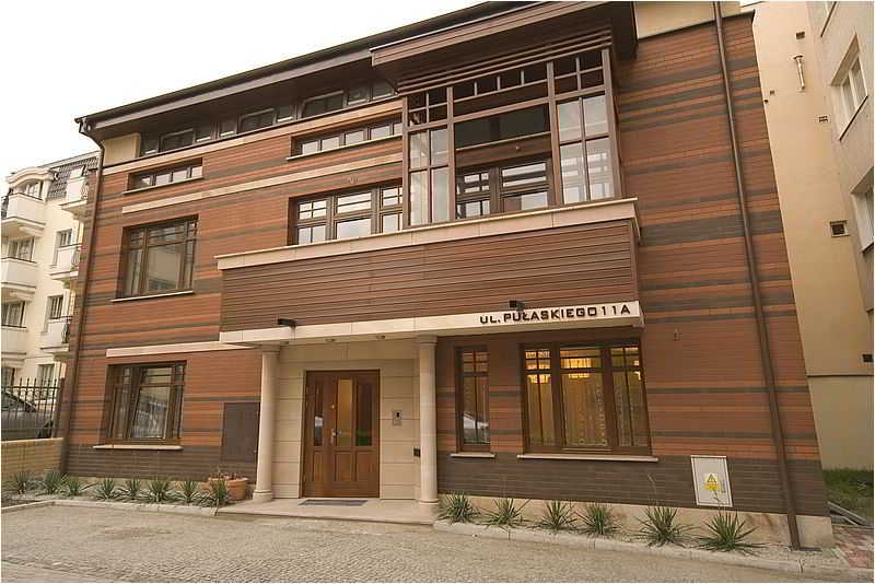 A modern residential building with wooden paneling and large windows exudes a cozy urban charm, ideal for travelers seeking upscale accommodation in a quiet neighborhood.
