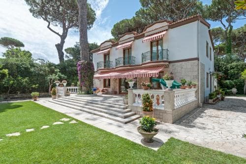 A charming Mediterranean villa with red-striped awnings and lush greenery exudes a serene and luxurious atmosphere, perfect for a tranquil vacation retreat.