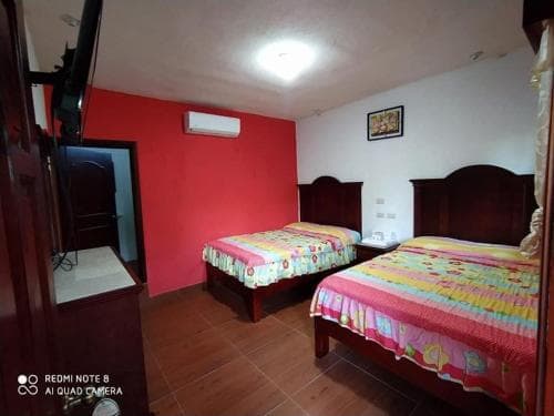 A cozy budget-friendly hotel room features two colorful beds against a vibrant red wall, creating a warm and inviting atmosphere ideal for travelers seeking affordable accommodations.
