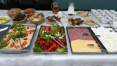 A vibrant buffet spread featuring fresh salads, assorted meats, cheeses, breads, and beverages creates an inviting atmosphere at a dining area, perfect for travelers seeking a diverse and hearty meal experience.