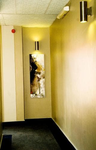 A warmly lit hotel corridor features modern wall art and sleek lighting, creating an inviting atmosphere ideal for travelers seeking comfort and style.