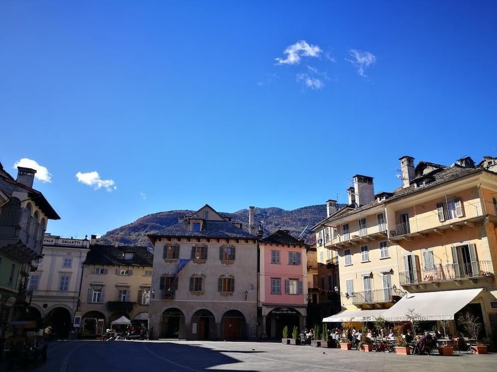 A serene European town square framed by colorful historic buildings under a clear blue sky, ideal for leisurely strolls and cultural exploration.