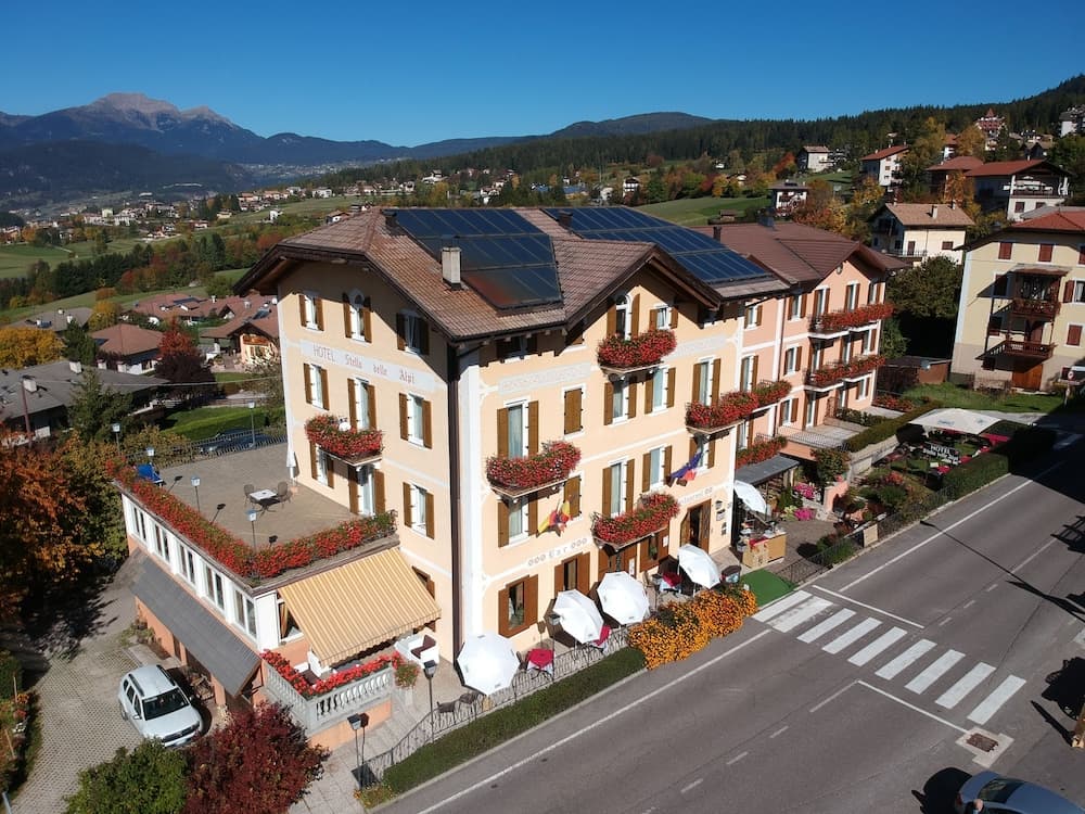 A charming hotel adorned with vibrant flower boxes stands invitingly in a picturesque mountain village, offering travelers a cozy retreat amidst scenic landscapes perfect for relaxation and exploration.