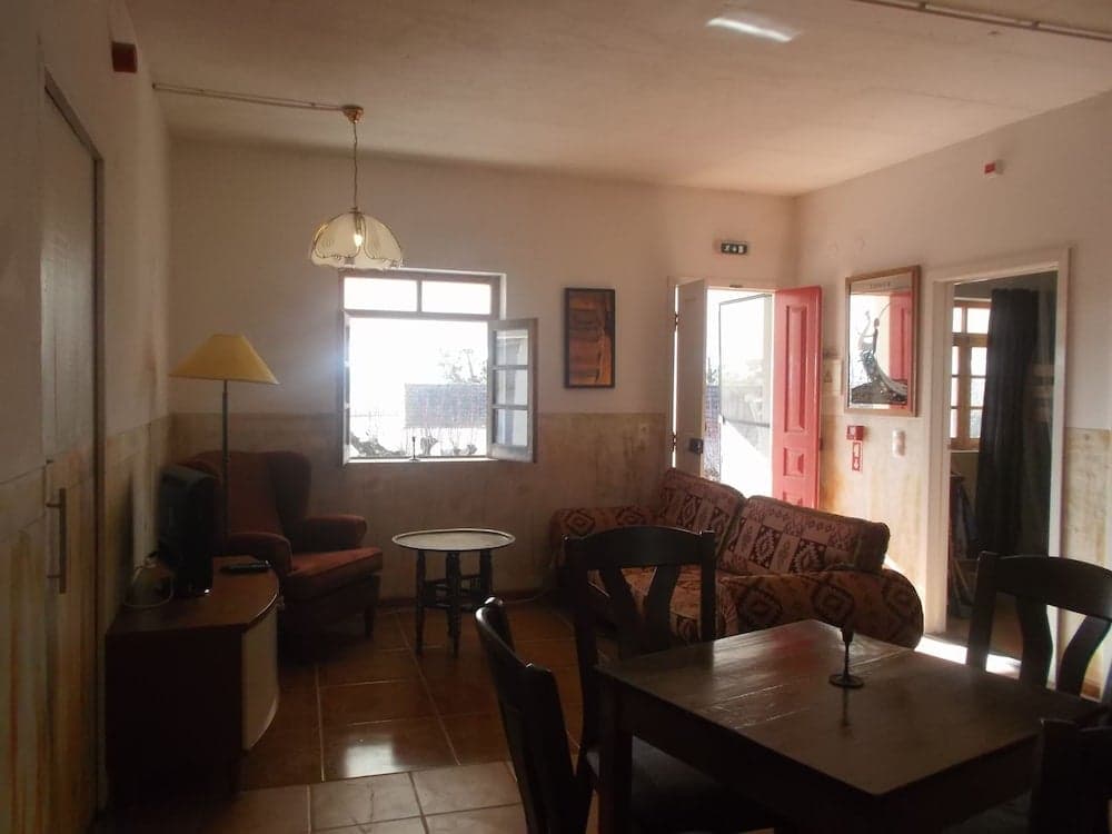 A cozy living room with tiled floors, warm lighting, and an open door leading to a balcony, ideal for travelers seeking a comfortable and inviting rental space.