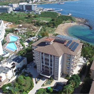 An aerial view captures a luxurious coastal resort with solar-paneled rooftops, lush greenery, and a serene beachfront, ideal for eco-conscious travelers seeking relaxation and sustainability.