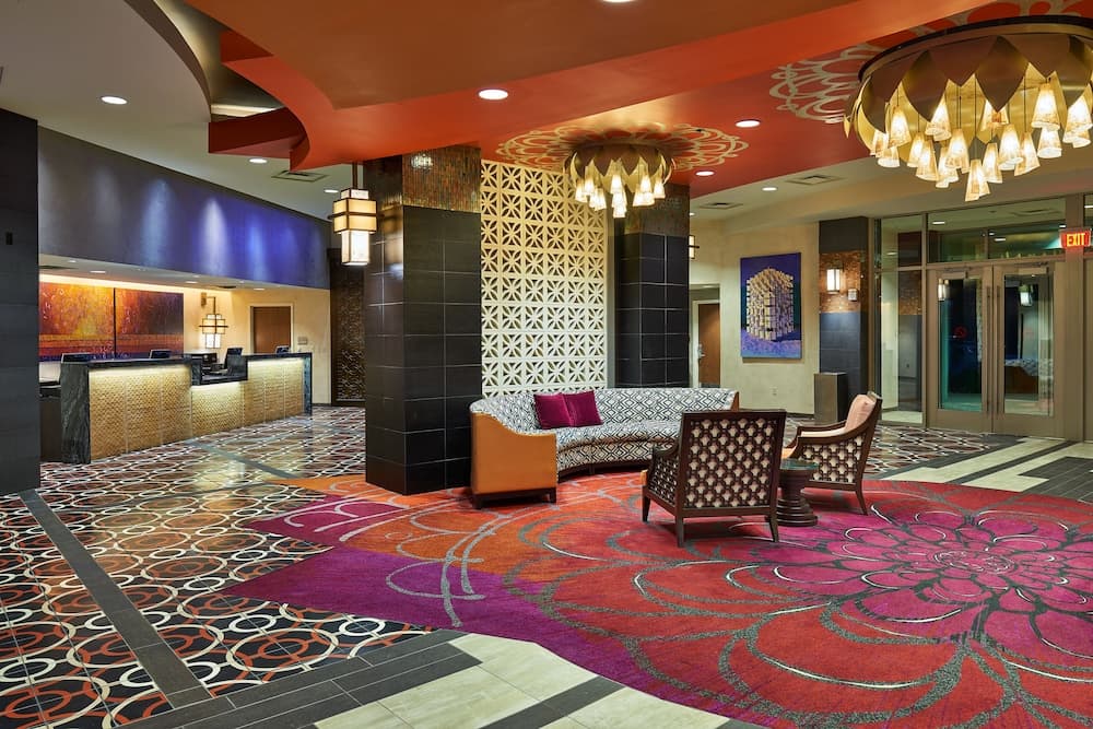 A vibrant hotel lobby features a colorful carpet, modern furnishings, and artistic decor, creating an inviting atmosphere ideal for travelers seeking comfort and style.