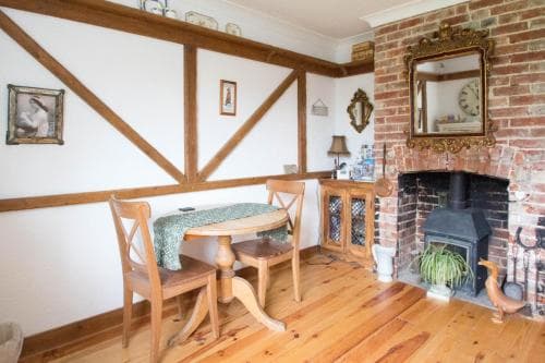 A cozy dining nook with wooden furniture, exposed brick fireplace, and rustic decor creates a warm, inviting atmosphere ideal for travelers seeking a quaint countryside retreat.