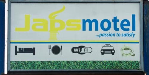 A vibrant motel sign featuring amenities like Wi-Fi, dining, and taxis sets the scene for a welcoming roadside stop, ideal for travelers seeking comfort and convenience.