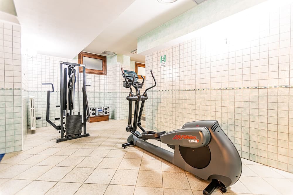 A serene indoor fitness room with tiled walls and floors features a Life Fitness elliptical trainer and weight machine, ideal for travelers seeking a quiet workout space.