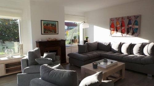 A cozy living room with modern furnishings, large windows letting in natural light, and vibrant wall art creates an inviting atmosphere ideal for a relaxing vacation rental stay.