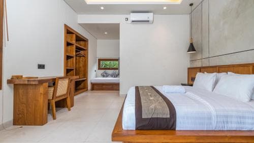 A serene minimalist bedroom with white walls, wooden furniture, and a small window view of greenery, ideal for travelers seeking a peaceful retreat in a modern lodge setting.
