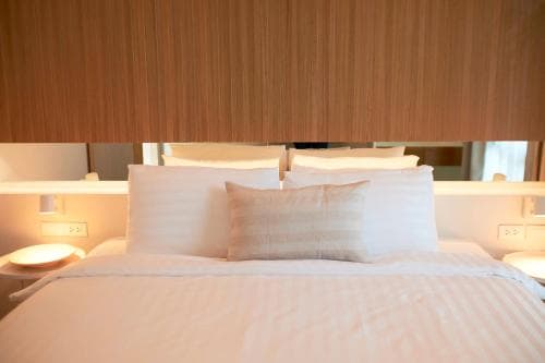 A serene hotel room features a cozy bed with plush white pillows against a modern wooden headboard, ideal for travelers seeking comfort and relaxation.
