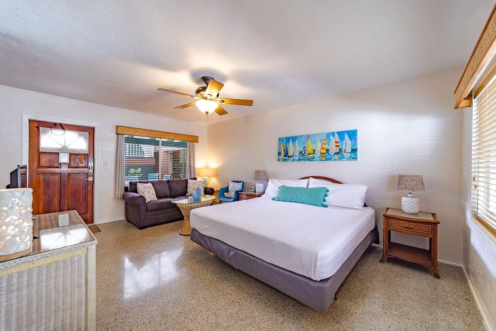 A cozy bedroom with a king-sized bed, vibrant sailboat artwork, and a comfortable seating area by the window, ideal for a relaxing vacation retreat.