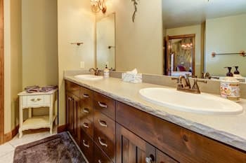 A cozy bathroom with warm lighting, wooden cabinetry, a granite countertop, and elegant fixtures creates an inviting atmosphere, perfect for travelers seeking comfort and style in their accommodations.
