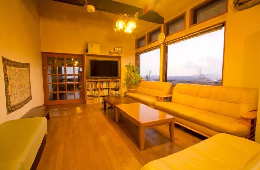 A cozy living room with warm lighting, wooden floors, yellow sofas, and large windows offering scenic views, ideal for travelers seeking a comfortable and inviting accommodation.