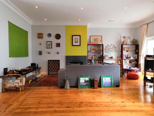 A cozy living room with wooden floors, eclectic decor, and vibrant wall colors offers a warm and inviting atmosphere ideal for a relaxing getaway or home tour inspiration.