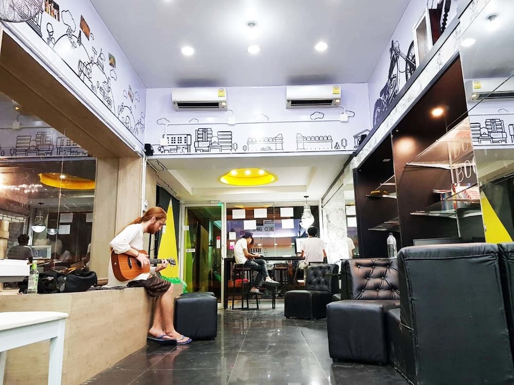 A cozy café with artistic wall murals, plush seating, and a musician playing guitar creates an inviting atmosphere ideal for travelers seeking a relaxing spot to unwind and enjoy live music.