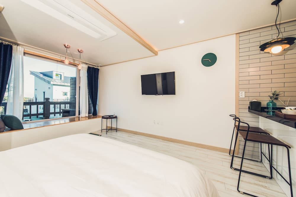 A cozy modern hotel room features a neatly made bed, sleek furniture, a wall-mounted TV, and a balcony view, ideal for travelers seeking comfort and style in their accommodations.