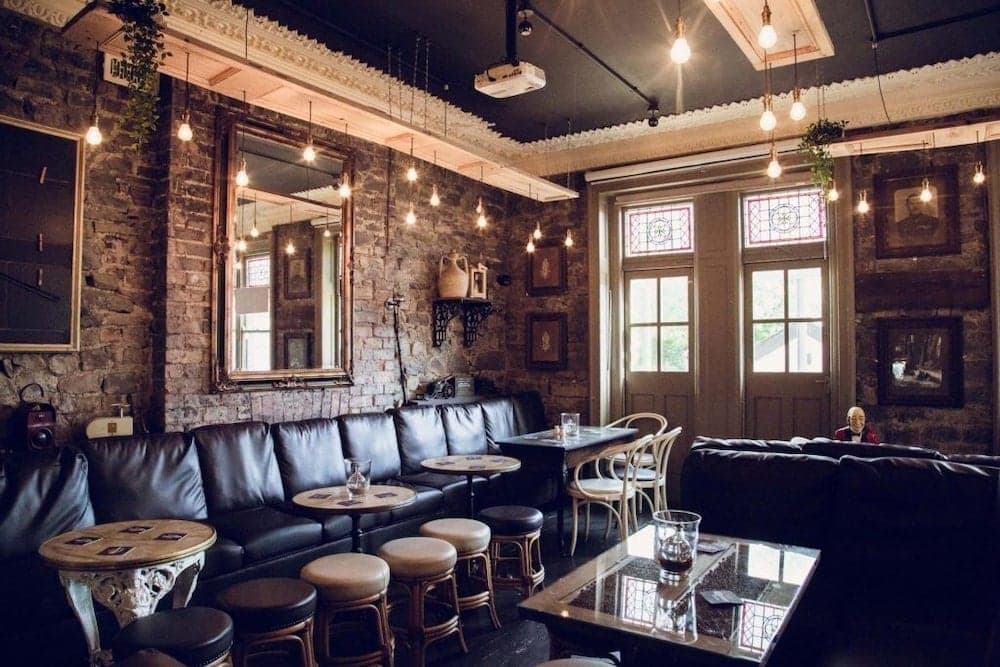 A cozy café with exposed brick walls, vintage decor, and soft lighting creates an inviting atmosphere perfect for travelers seeking a relaxing spot to unwind and enjoy a quiet moment.