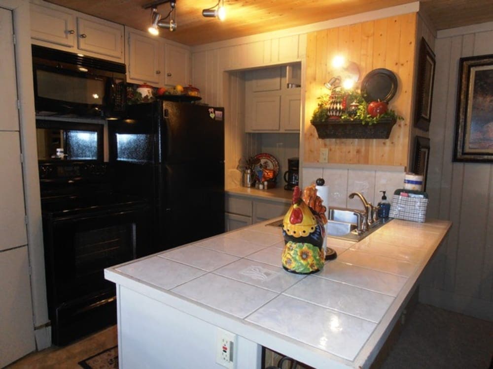 A cozy cabin kitchen with wooden walls, tiled countertops, and rustic decor creates a warm atmosphere ideal for family gatherings and culinary adventures.