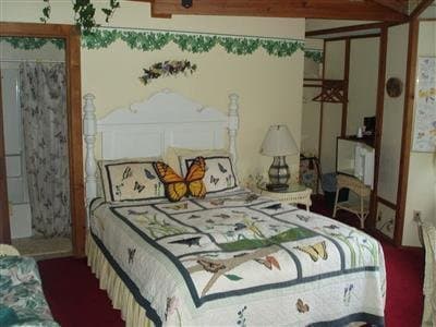 A cozy bedroom with butterfly-themed bedding and decor exudes warmth and charm, perfect for travelers seeking a serene retreat in a quaint lodge or bed-and-breakfast setting.