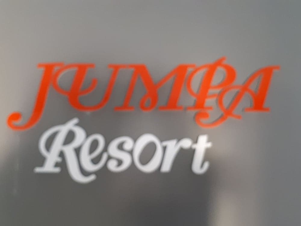 A close-up of the "JUMPA Resort" sign in orange and white script against a neutral background evokes a modern and inviting atmosphere, ideal for travelers seeking upscale accommodation options.