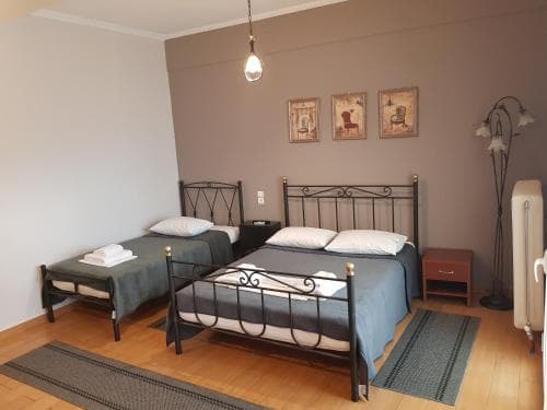 A cozy hotel room features two neatly made beds with metal frames, framed artwork on the walls, and soft lighting, creating a welcoming atmosphere ideal for travelers seeking comfort and relaxation.