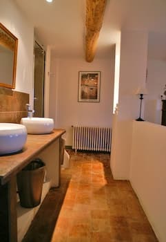 A cozy bathroom with rustic stone flooring, wooden beams, and modern fixtures bathed in warm light, ideal for travelers seeking a serene and stylish retreat.