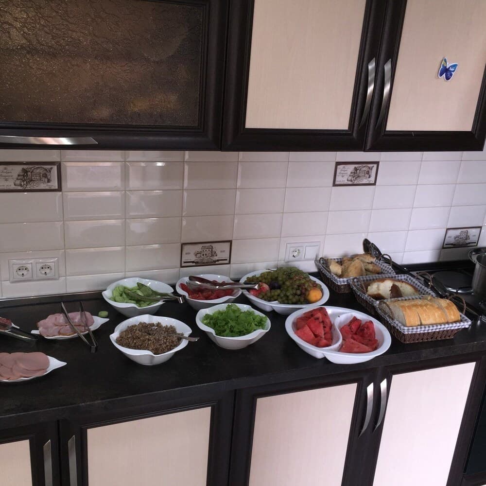 A cozy kitchen scene featuring a buffet of fresh fruits, vegetables, bread, and meats on a sleek countertop, ideal for travelers seeking a self-catering accommodation experience.