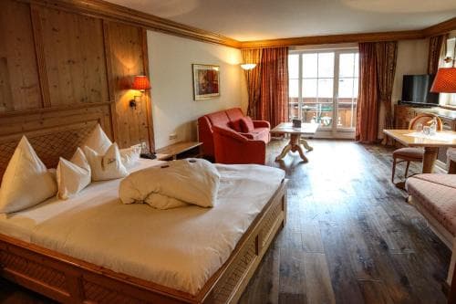 A cozy hotel room with wooden furnishings, warm lighting, and a balcony view offers a relaxing retreat for travelers seeking comfort in a mountain lodge setting.