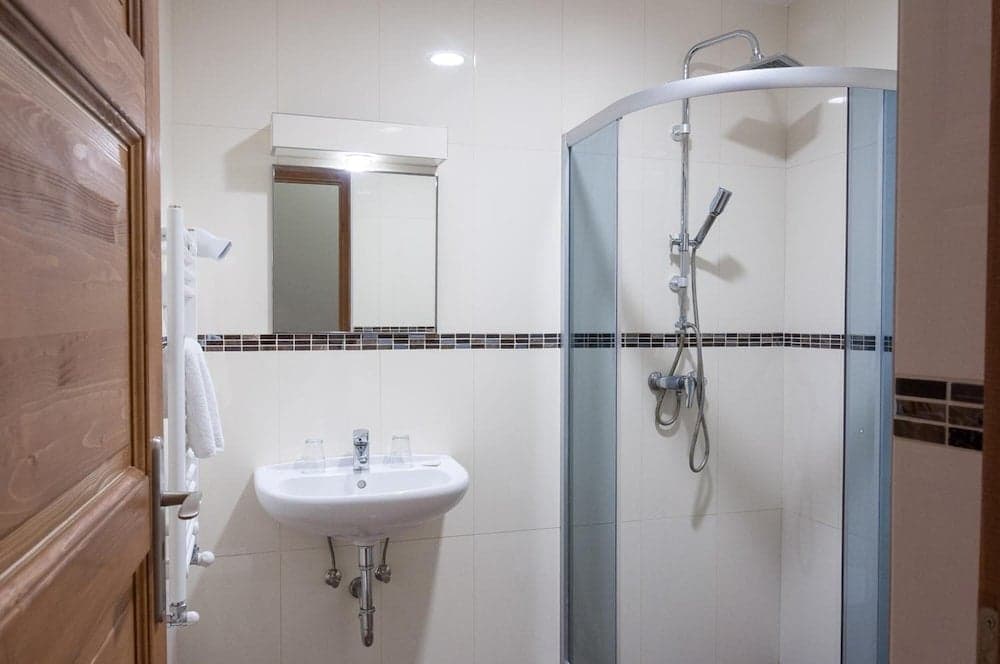 A clean and modern bathroom featuring a glass-enclosed shower, white sink with chrome fixtures, and neatly folded towels on a rack, ideal for travelers seeking comfort and hygiene in their accommodations.