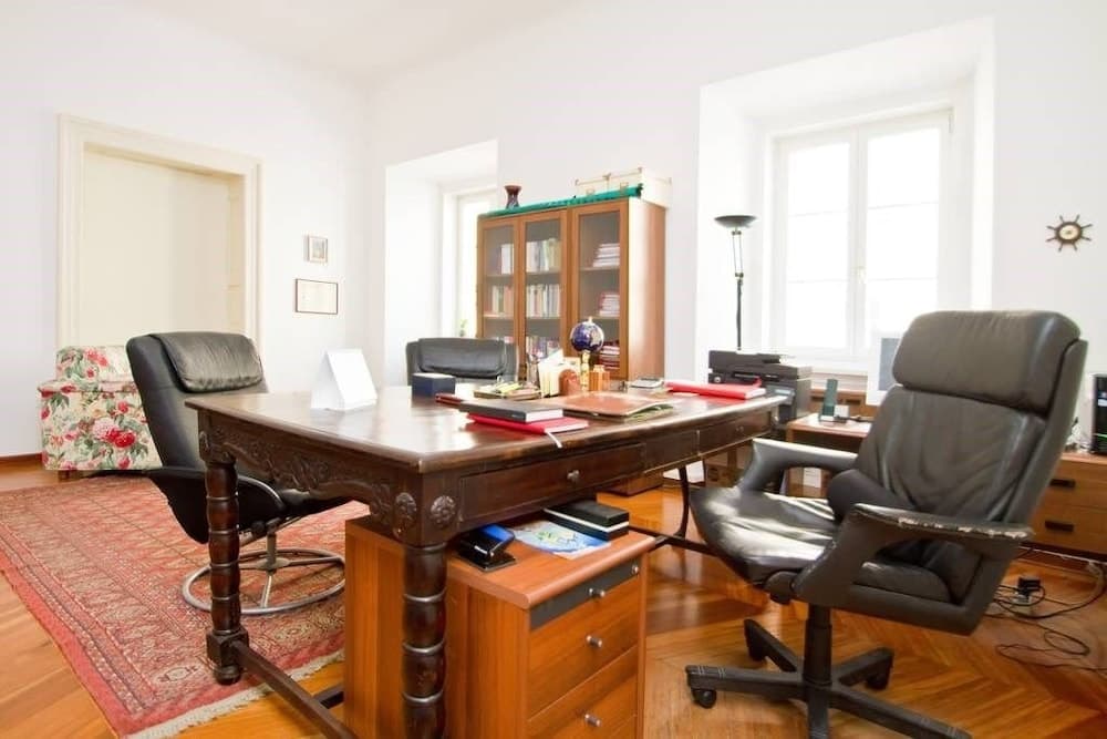 A cozy home office with wooden furniture, leather chairs, and a patterned rug exudes a professional yet comfortable atmosphere, ideal for travelers seeking a serene workspace during their stay.