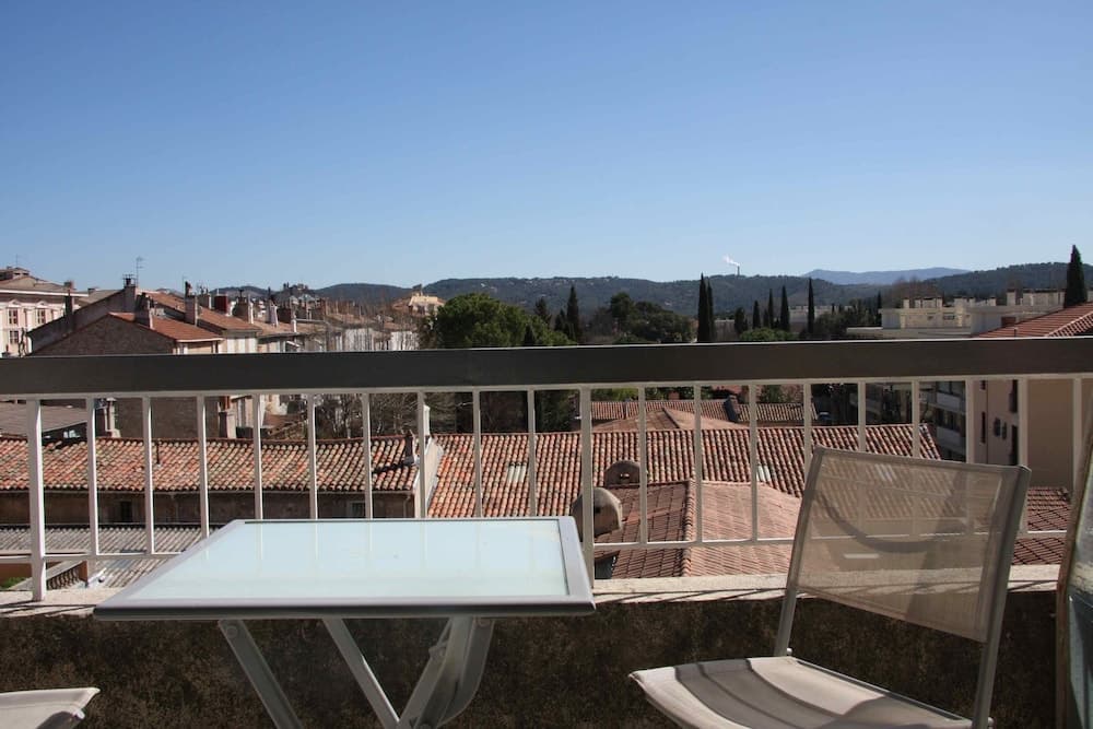 A serene balcony view overlooking tiled rooftops and distant hills under a clear blue sky, perfect for a tranquil European city getaway.