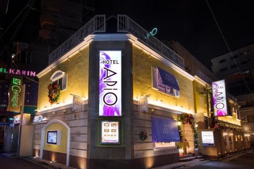 A vibrant night scene showcases the illuminated Hotel Ario in an urban setting, featuring modern signage and festive decorations, ideal for travelers seeking a lively city stay.