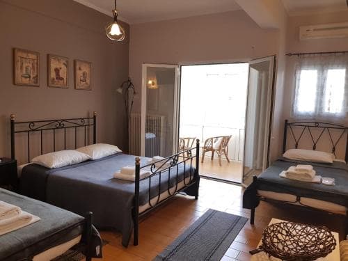 A cozy hotel room with two beds, framed artwork on the walls, and a balcony view, exudes a welcoming atmosphere ideal for travelers seeking comfort and relaxation.