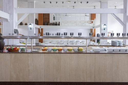 A bright, modern buffet area with neatly arranged food options invites travelers to enjoy a self-serve meal in a spacious dining hall, ideal for hotel guests seeking convenience and variety.