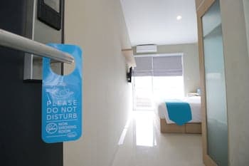 A serene hotel room hallway features a "Do Not Disturb" sign on the door handle, leading to a cozy bedroom with natural light streaming through blinds, ideal for travelers seeking relaxation and privacy.