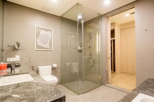 A modern bathroom with a sleek glass shower enclosure, marble countertop, and minimalist decor creates a serene atmosphere ideal for travelers seeking comfort and style in their accommodations.