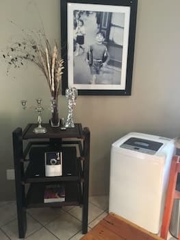 A cozy indoor corner features a wooden shelf adorned with decorative items like dried flowers and trophies, framed by a nostalgic black-and-white photograph above, creating a warm, personal atmosphere ideal for home travelers seeking comfort and memories.