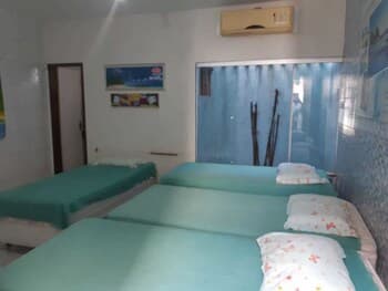 A cozy budget-friendly hostel room features teal beds against a blue-tiled wall, creating a serene atmosphere ideal for travelers seeking affordable accommodations.
