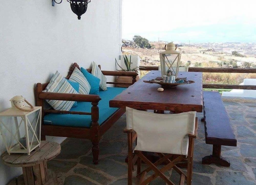A serene outdoor terrace features rustic wooden furniture adorned with blue cushions and lanterns, offering a tranquil retreat with panoramic views ideal for relaxing getaways.
