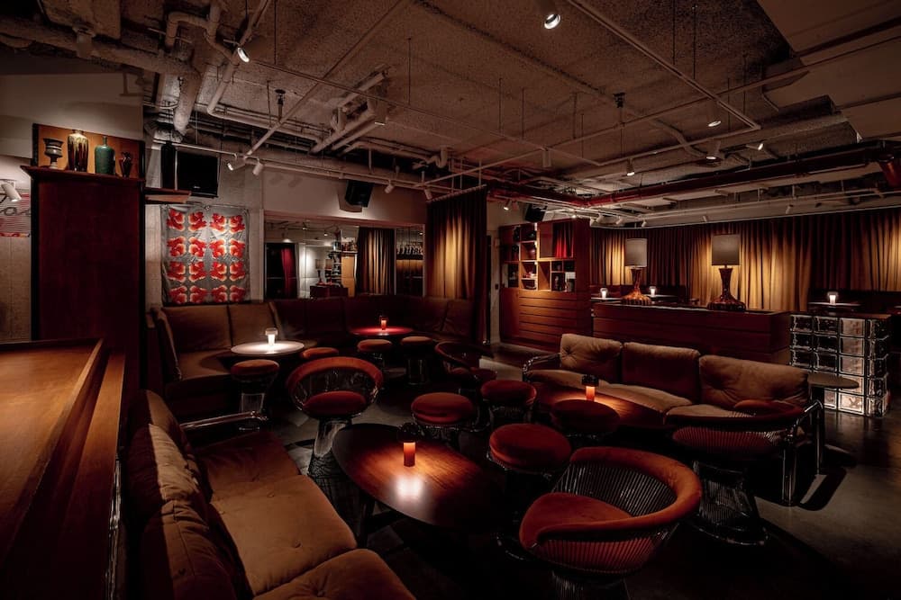 A cozy, dimly-lit lounge with plush seating, warm lighting, and industrial ceiling details creates an intimate atmosphere ideal for evening social gatherings or romantic dates.