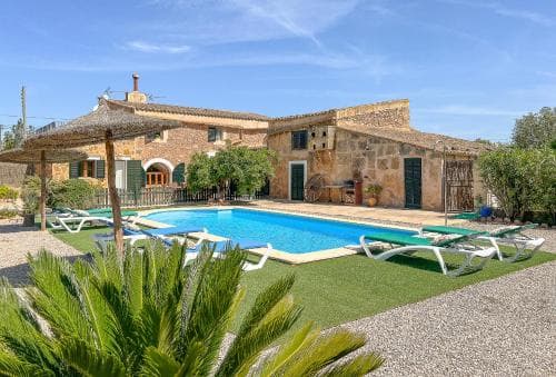 A serene Mediterranean villa with a vibrant blue pool, lush greenery, and rustic stone architecture offers an idyllic retreat for travelers seeking relaxation and privacy.