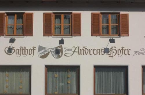 A charming European guesthouse with traditional wooden shutters and a painted signboard exudes a cozy, inviting atmosphere perfect for travelers seeking a quaint lodging experience.