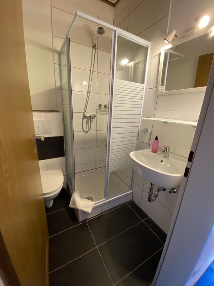 A modern bathroom with a glass-enclosed shower, sleek sink, and neatly arranged toiletries offers a clean and functional space ideal for travelers seeking comfort in accommodations.