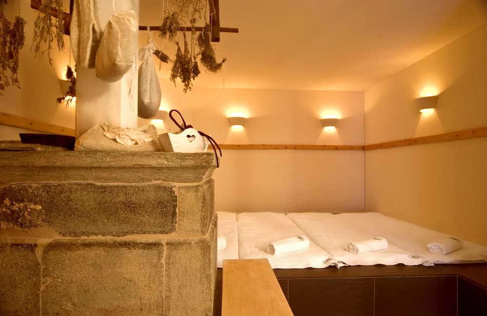A serene spa relaxation room features soft lighting, stone steps, neatly folded towels, and hanging herbs, ideal for travelers seeking tranquility and rejuvenation.