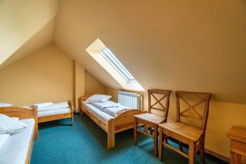 A cozy attic bedroom with wooden furniture, a skylight, and green carpet offers a serene retreat for travelers seeking a quaint and comfortable stay.